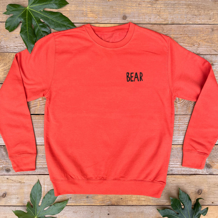 orange jumper with bear text